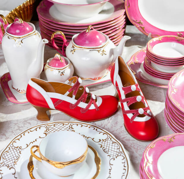 Scarpe personalizzate rosse firmate Vladì Shoes in mezzo a tazze di porcellana